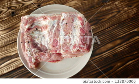 prepares a piece of raw meat on a white plate for cooking prepares a piece of raw meat on a white plate for cooking 138870006