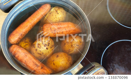 Cooking potatoes and carrots in a pot on the stove during meal preparation Cooking potatoes and carrots in a pot on the stove during meal preparation 138870096