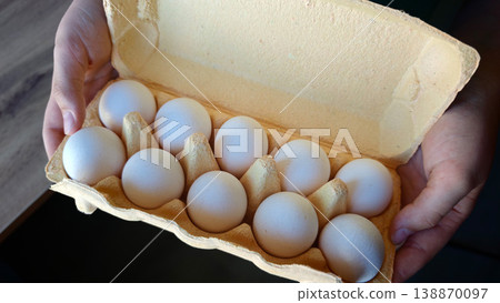 Hands holding a carton of ten eggs in a kitchen setting during the day Hands holding a carton of ten eggs in a kitchen setting during the day 138870097