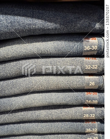 Stacked denim jeans showcasing various sizes in retail store, ideal for fashion background Stacked denim jeans showcasing various sizes in retail store, ideal for fashion background 138870207
