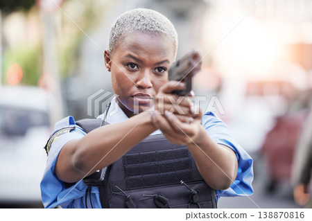 Gun, serious and female police officer in the city for an arrest to stop crime in a street. Upset, young and African woman security guard with pistol for safety, authority and law enforcement in town Gun, serious and female police officer in the city for an arrest to stop crime in a street. Upset, young and African woman security guard with pistol for safety, authority and law enforcement in town 138870816