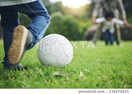 Child, legs and kick soccer ball on grass for fun activity, childhood or playing in the park. Playful little boy in sports game or match for score, point or goal on green field in the nature outdoors 138870835