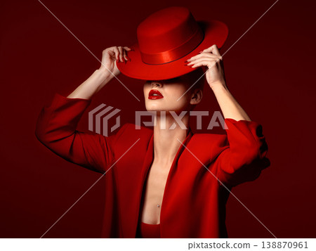 Woman, red aesthetic and hat in studio with makeup art, thinking and mystery with couture, vision and background. Girl, model and high fashion with suit, mindset and facial paint for cosmetic beauty 138870961