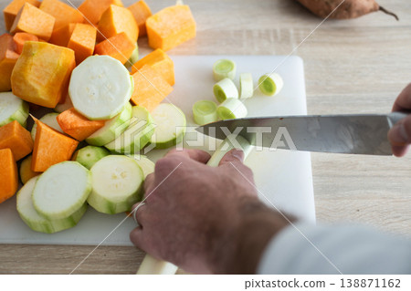 Cutting leek with mixed fresh vegetables on cutting board in kitchen 138871162