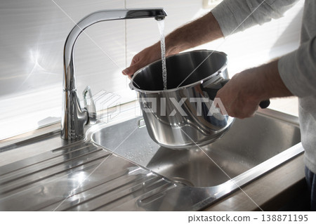 Filling pot with water from kitchen faucet over stainless steel sink Filling pot with water from kitchen faucet over stainless steel sink 138871195