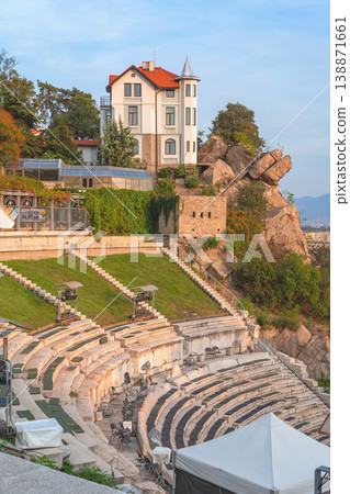 Plovdiv ancient theatre with stone seating, house on rocky hill showing architecture and cultural landmark in Plovdiv Bulgaria. Concept of history heritage travel tourism destination city culture Plovdiv ancient theatre with stone seating, house on rocky hill showing architecture and cultural landmark in Plovdiv Bulgaria. Concept of history heritage travel tourism destination city culture 138871661