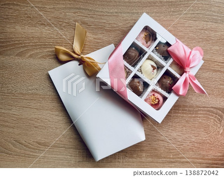 Delicious, sweet handmade chocolates made of white and milk chocolate with whole nuts in a gift box on a light background. High quality photo Delicious, sweet handmade chocolates made of white and milk chocolate with whole nuts in a gift box on a light background. High quality photo 138872042