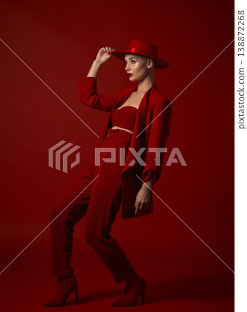 Aesthetic, fashion and a woman walking on a red studio background for elegant or trendy style. Runway model, art or beauty with a confident young female person looking edgy and classy in a bold suit Aesthetic, fashion and a woman walking on a red studio background for elegant or trendy style. Runway model, art or beauty with a confident young female person looking edgy and classy in a bold suit 138872268