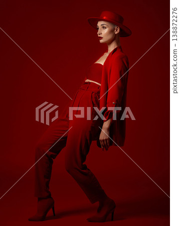 Luxury, fashion and a woman runway model on a red studio background for elegant or trendy style. Aesthetic, art and confident with a young female person walking in an edgy or classy suit for beauty 138872276