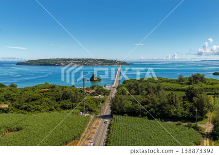 A vertical aerial photograph of the bridge leading to Kouri Island in Okinawa, taken directly above, against the backdrop of the emerald green sea. A vertical aerial photograph of the bridge leading to Kouri Island in Okinawa, taken directly above, against the backdrop of the emerald green sea. 138873392