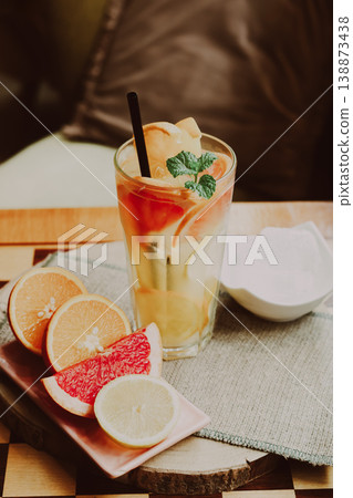 A refreshing cold citrus drink made with orange, lemon, and grapefruit, placed on a coffee table, natural light, minimal composition. A refreshing cold citrus drink made with orange, lemon, and grapefruit, placed on a coffee table, natural light, minimal composition. 138873438