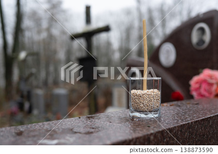 Glass with barley and candle on grave in misty cemetery Glass with barley and candle on grave in misty cemetery 138873590