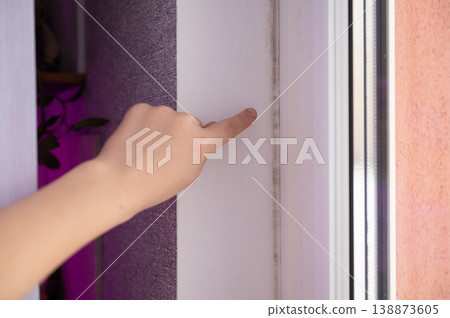 Female hand pointing at mold on wall near window frame Female hand pointing at mold on wall near window frame 138873605