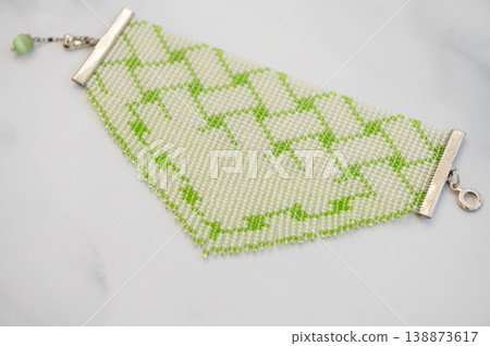 Elegant green and white beaded bracelet on marble surface Elegant green and white beaded bracelet on marble surface 138873617