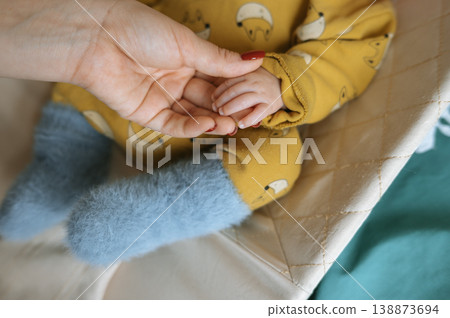 Baby hand holding adult hand in cozy nursery setting Baby hand holding adult hand in cozy nursery setting 138873694