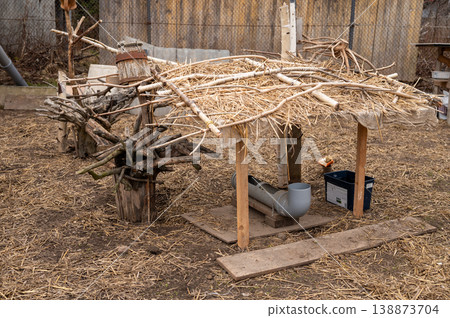 Thatched chicken shelter standing on farm yard ground Thatched chicken shelter standing on farm yard ground 138873704