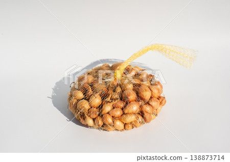 Mesh bag of small onions on white background with shadow 138873714