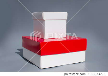 Stacked red and white gift boxes on gray background Stacked red and white gift boxes on gray background 138873715