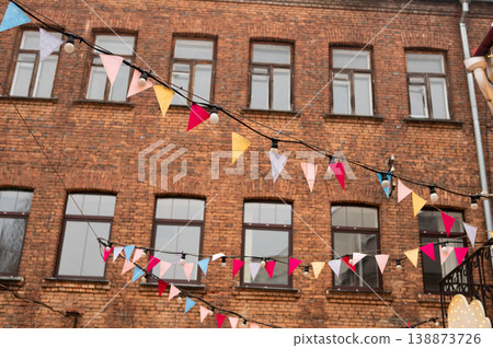 Colorful pennant flags on brick building at outdoor festive event 138873726