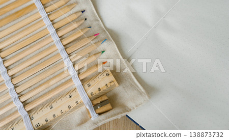 Colored pencils and ruler on canvas wrap with open blank notebook Colored pencils and ruler on canvas wrap with open blank notebook 138873732