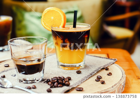 A glass of fresh orange juice and a cup of espresso on a coffee table, refreshing and energizing drinks for a hot summer day, natural light, minimal composition, vibrant lifestyle scene. A glass of fresh orange juice and a cup of espresso on a coffee table, refreshing and energizing drinks for a hot summer day, natural light, minimal composition, vibrant lifestyle scene. 138873758