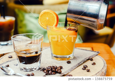 A glass of fresh orange juice and a cup of espresso on a coffee table, refreshing and energizing drinks for a hot summer day, natural light, minimal composition, vibrant lifestyle scene. A glass of fresh orange juice and a cup of espresso on a coffee table, refreshing and energizing drinks for a hot summer day, natural light, minimal composition, vibrant lifestyle scene. 138873759