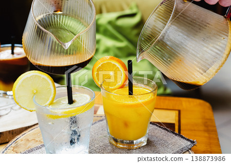 A glass of Espresso Sunrise on a coffee table, decorated with slice of orange. Refreshing and energizing drinks for a hot summer day, natural light, minimal composition, vibrant lifestyle scene. 138873986