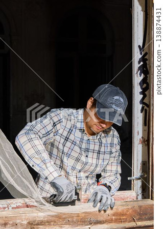 Worker restoring window with safety gear and tools present Worker restoring window with safety gear and tools present 138874431