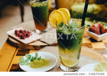 Frozen lemon tea with added matcha in a glass, standing on a wooden table in a cafe 138874580