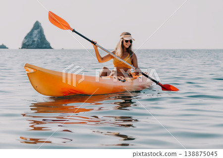 Kayaking, Woman, Sea: Kayaking woman enjoys scenic view on a calm sea near rock formations. Kayaking, Woman, Sea: Kayaking woman enjoys scenic view on a calm sea near rock formations. 138875045
