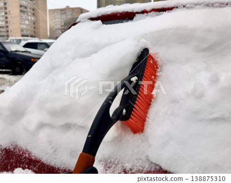 car brush with a scraper in black and orange on a background of snow-white snow on a car in winter car brush with a scraper in black and orange on a background of snow-white snow on a car in winter 138875310