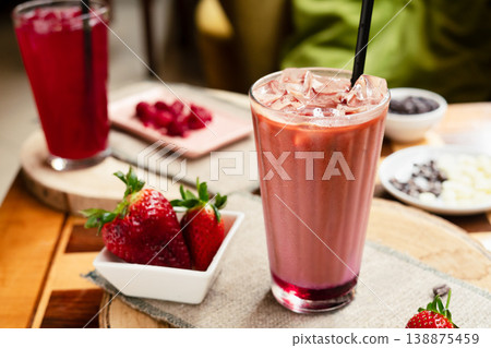 Strawberry raspberry smoothie on a wooden table, with fresh strawberries on a plate in the background, healthy summer drink, vibrant colors, natural light. Strawberry raspberry smoothie on a wooden table, with fresh strawberries on a plate in the background, healthy summer drink, vibrant colors, natural light. 138875459