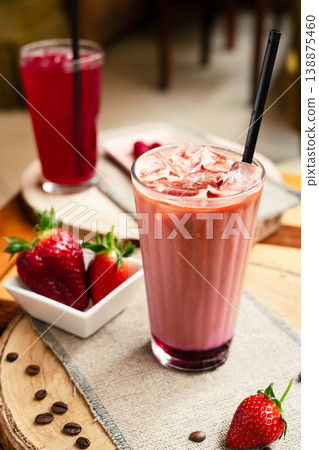Strawberry raspberry smoothie on a wooden table, with fresh strawberries on a plate in the background, healthy summer drink, vibrant colors, natural light. 138875460