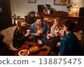 A group of friends enjoying snacks and drinks at a cozy home gathering 138875475
