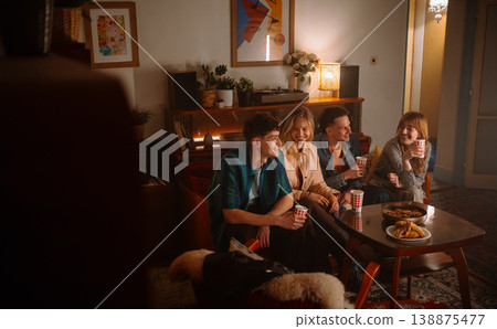 Friends enjoy a cozy evening gathering together, relishing tasty snacks and drinks Friends enjoy a cozy evening gathering together, relishing tasty snacks and drinks 138875477