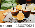 A glass of Espresso Sunrise on a coffee table, decorated with slice of orange. Refreshing and energizing drinks for a hot summer day, natural light, minimal composition, vibrant lifestyle scene. 138875624