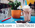 Chocolate smoothie with a creamy flavor in a glass on a wooden table, decorated with  chocolate cookies, healthy summer drink, vibrant colors, natural light. 138875630