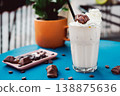 Smoothie with a creamy flavor in a glass on a wooden table, decorated with  chocolate wafer, healthy summer drink, vibrant colors, natural light. 138875636