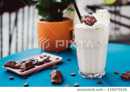 Smoothie with a creamy flavor in a glass on a wooden table, decorated with  chocolate wafer, healthy summer drink, vibrant colors, natural light. 138875636