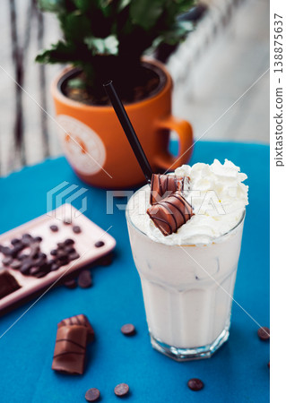 Smoothie with a creamy flavor in a glass on a wooden table, decorated with  chocolate wafer, healthy summer drink, vibrant colors, natural light. 138875637