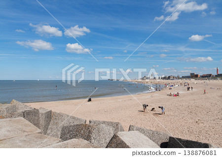 Sunny beach with people relaxing by the sea and blue sky 138876081
