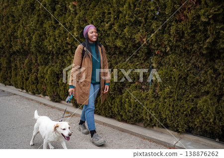 Young adult woman walking dog on street Young adult woman walking dog on street 138876262