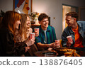 Cheerful group of young diverse friends laughing and toasting with cups at a cozy home party 138876405