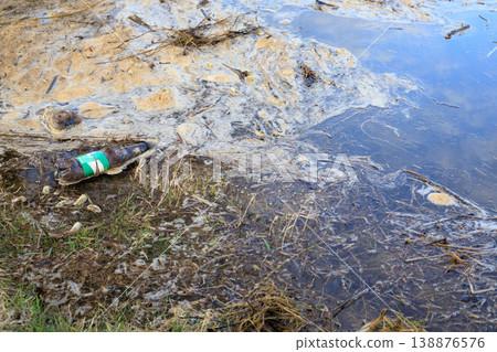 Water pollution. Plastic bottles and dirty foam on the surface of the water. 138876576