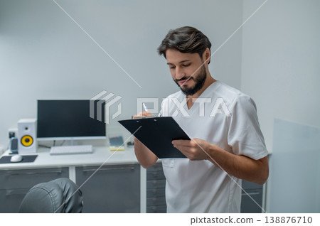 Young caucasian dentist in lab coat looking confident and contented Young caucasian dentist in lab coat looking confident and contented 138876710