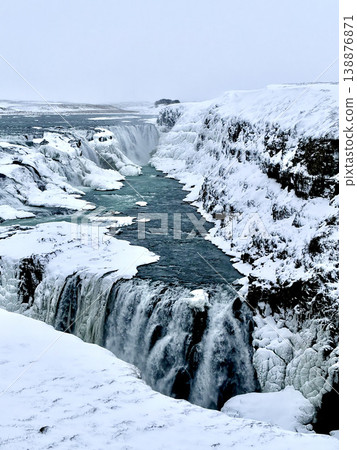 Close-up vertical shot of Gullfoss waterfall in Iceland during winter with ice and rushing water. Close-up vertical shot of Gullfoss waterfall in Iceland during winter with ice and rushing water. 138876871