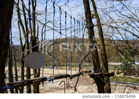 Suspended rope course with wooden planks between trees in outdoor adventure park Suspended rope course with wooden planks between trees in outdoor adventure park 138876896