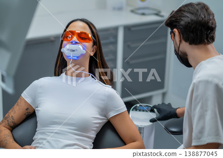 Young woman in protective eyeglasses sitting in a chair in the dentists office Young woman in protective eyeglasses sitting in a chair in the dentists office 138877045