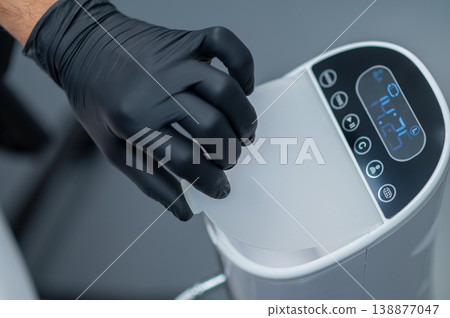 Close up of a medical device and a hu,an hand in black glove switching it 138877047