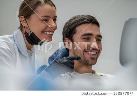 Dentist and patient admiring result in mirror Dentist and patient admiring result in mirror 138877074